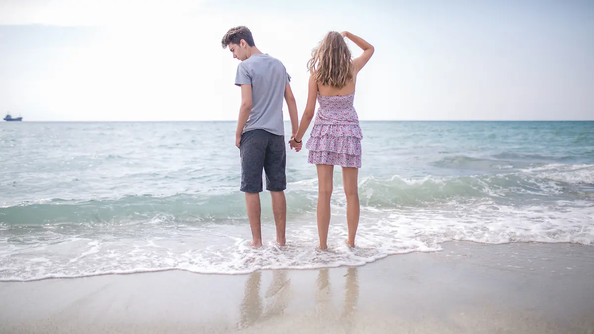 Ein Paar steht im Urlaub am Strand im Meer und scheint sichtlich schlecht gelaunt zu sein, als ob sie vorher Streit hatten.