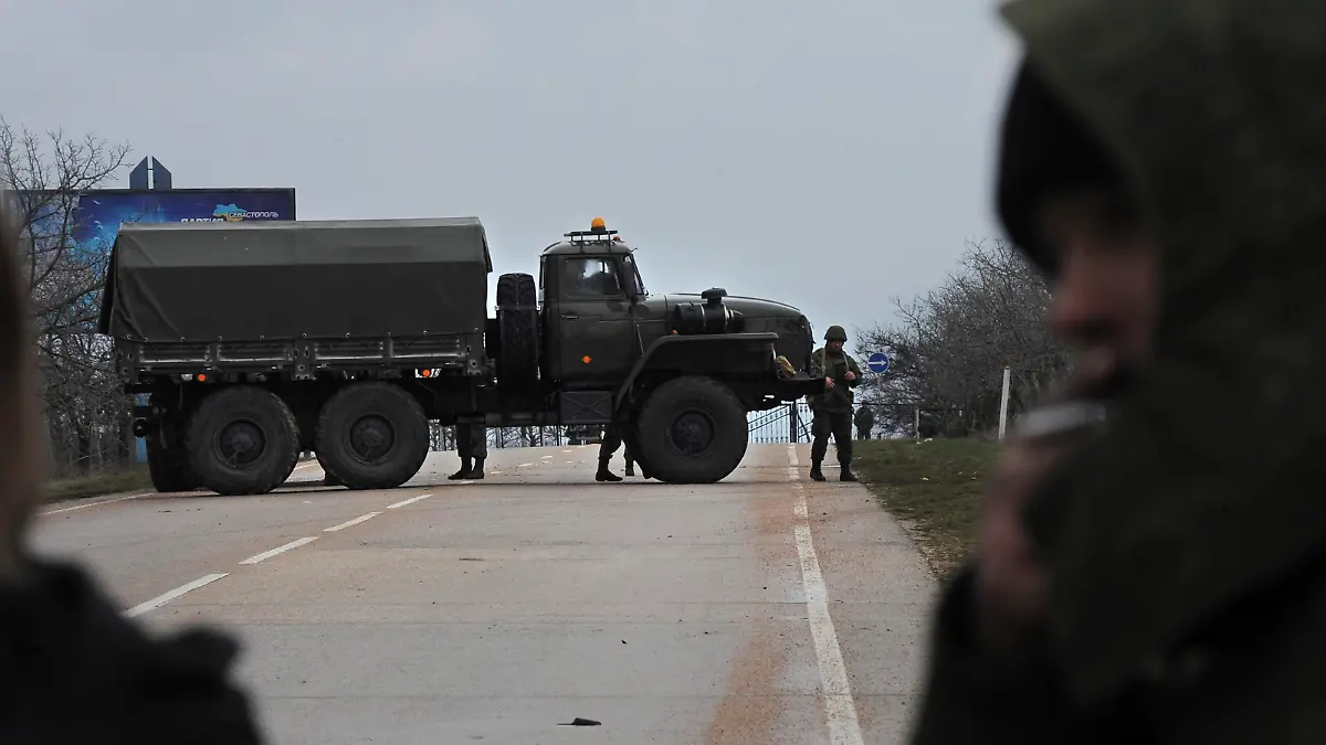 Russian troops block the road way towards the military airport at the Black Sea port of Sevastopol in Crimea, Ukraine, Friday, Feb. 28, 2014. Heightened security is evident with Russian military around Sevastopol, the location for Russia military bases, military airport and Naval Base, while unidentified armed men wearing uniforms without insignia were patrolling another airport serving the regional capital, Ukraine's new Interior Minister Arsen Avakov said on Friday.(AP Photo/Andrew Lubimov)