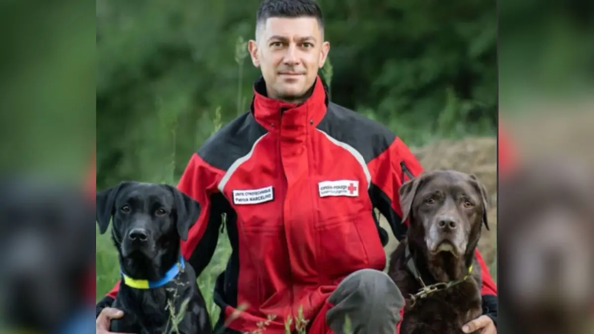 Hundeführer Patrick Marcelino und zwei Rettungshunde sitzen auf dem Rasen. 