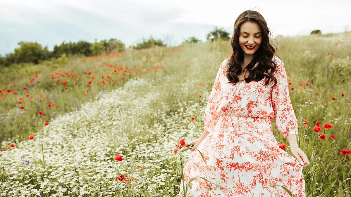 After months of isolation finally free in the nature, young beautiful lady in the green fields of early summer
