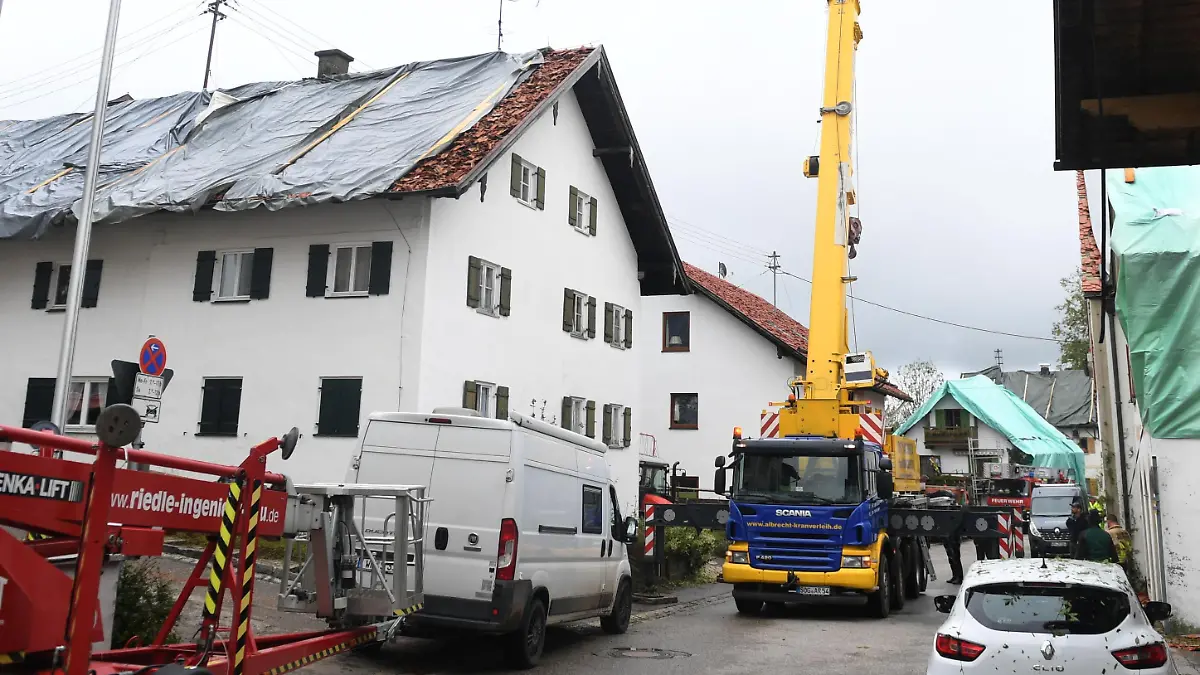 27.08.2023, Bayern, Bad Bayersoien: Nach dem Unwetter im Landkreis Garmisch-Partenkirchen sind die Dächer mehrerer Wohnhäuser mit Planen provisorisch abgedeckt. Aufgrund schwerer Unwetterschäden rief das Landratsamt Garmisch-Partenkirchen für den Ort mit rund 1300 Einwohnern am Sonntag den Katastrophenfall aus. 80 Prozent der Gebäude in dem Ort sollen schwer beschädigt sein. Foto: Felix Hörhager/dpa +++ dpa-Bildfunk +++