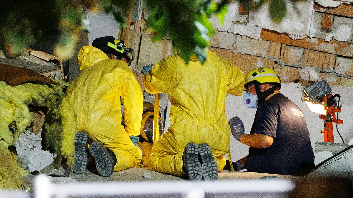 THW-Helfer in Schutzkleidung räumen Trümmer beiseite, um an den letzten noch verschütteten Toten zu gelangen.
