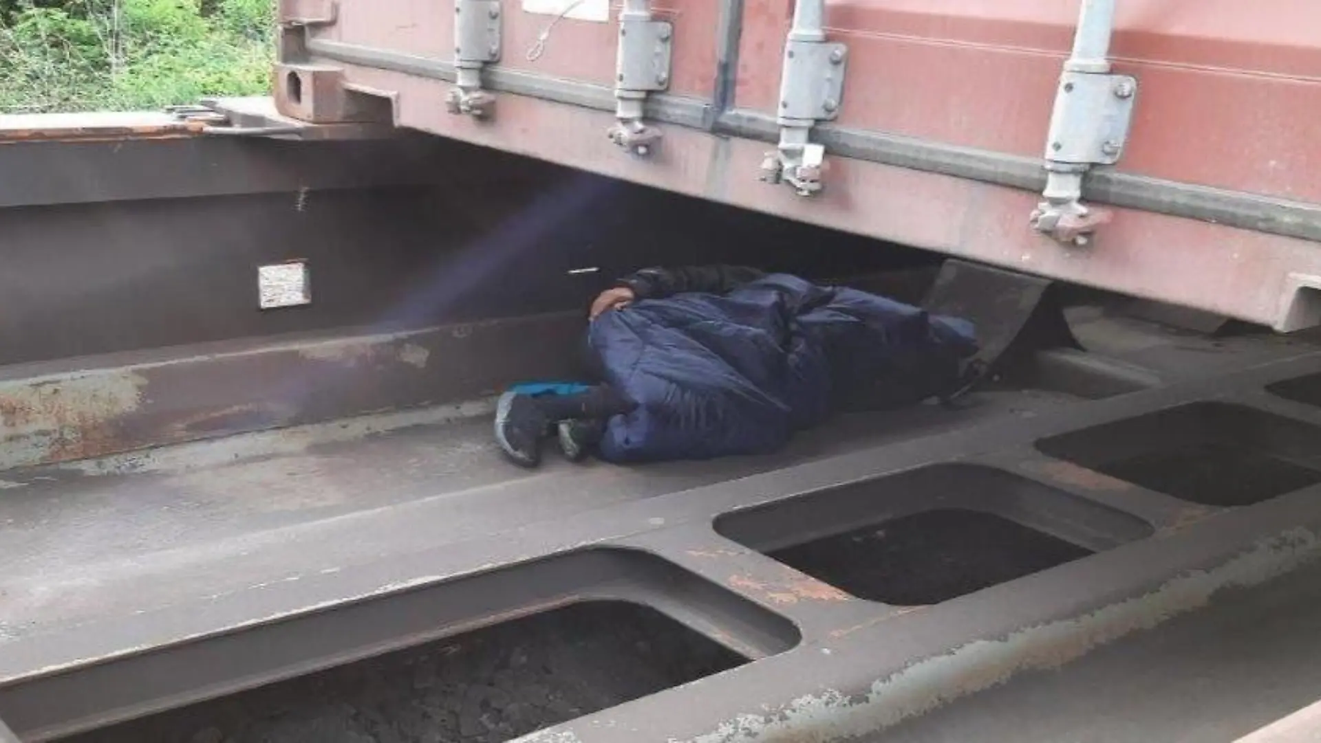 Foto: Person schlafend unter Container des Güterzuges