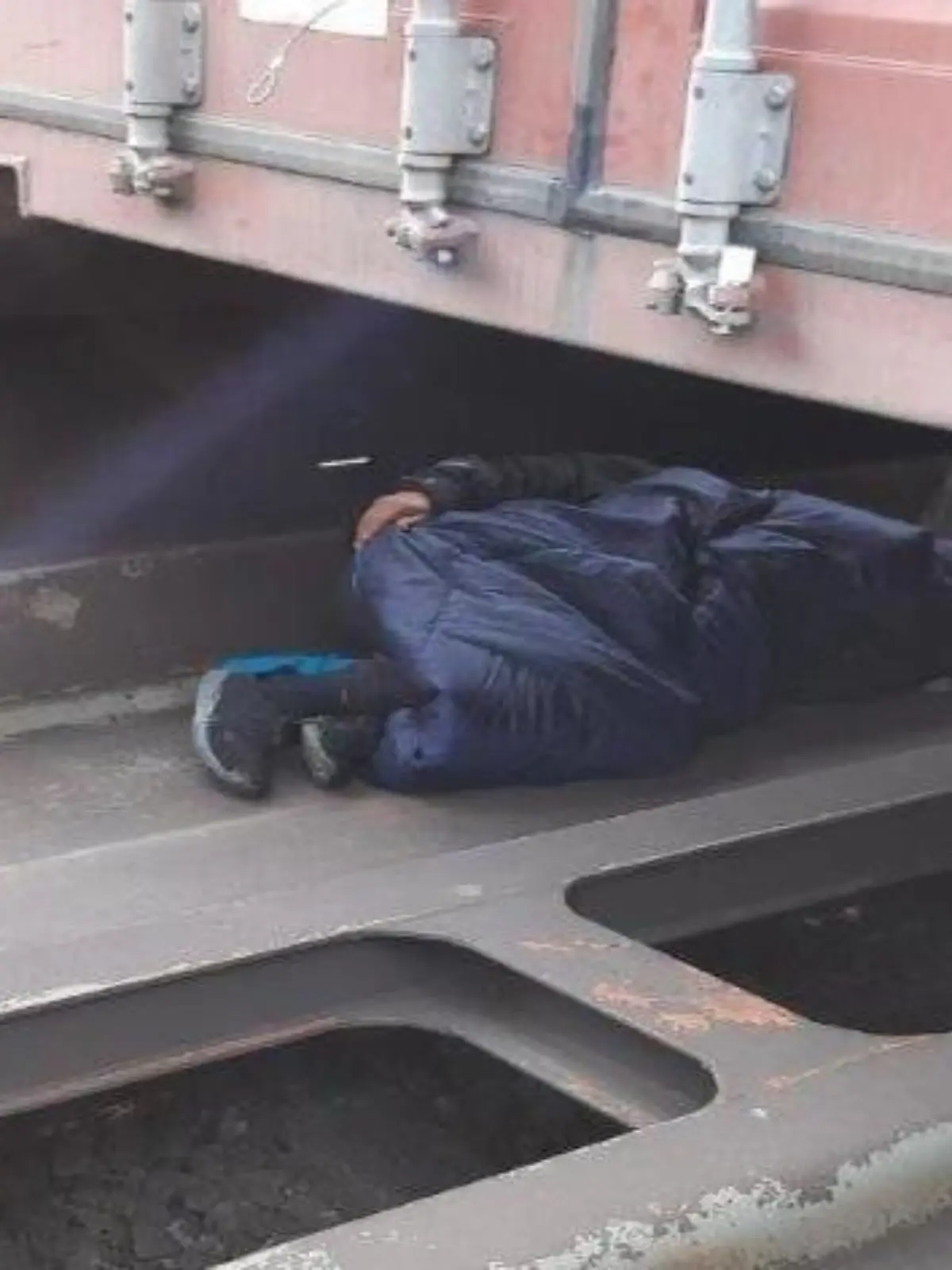 Foto: Person schlafend unter Container des Güterzuges