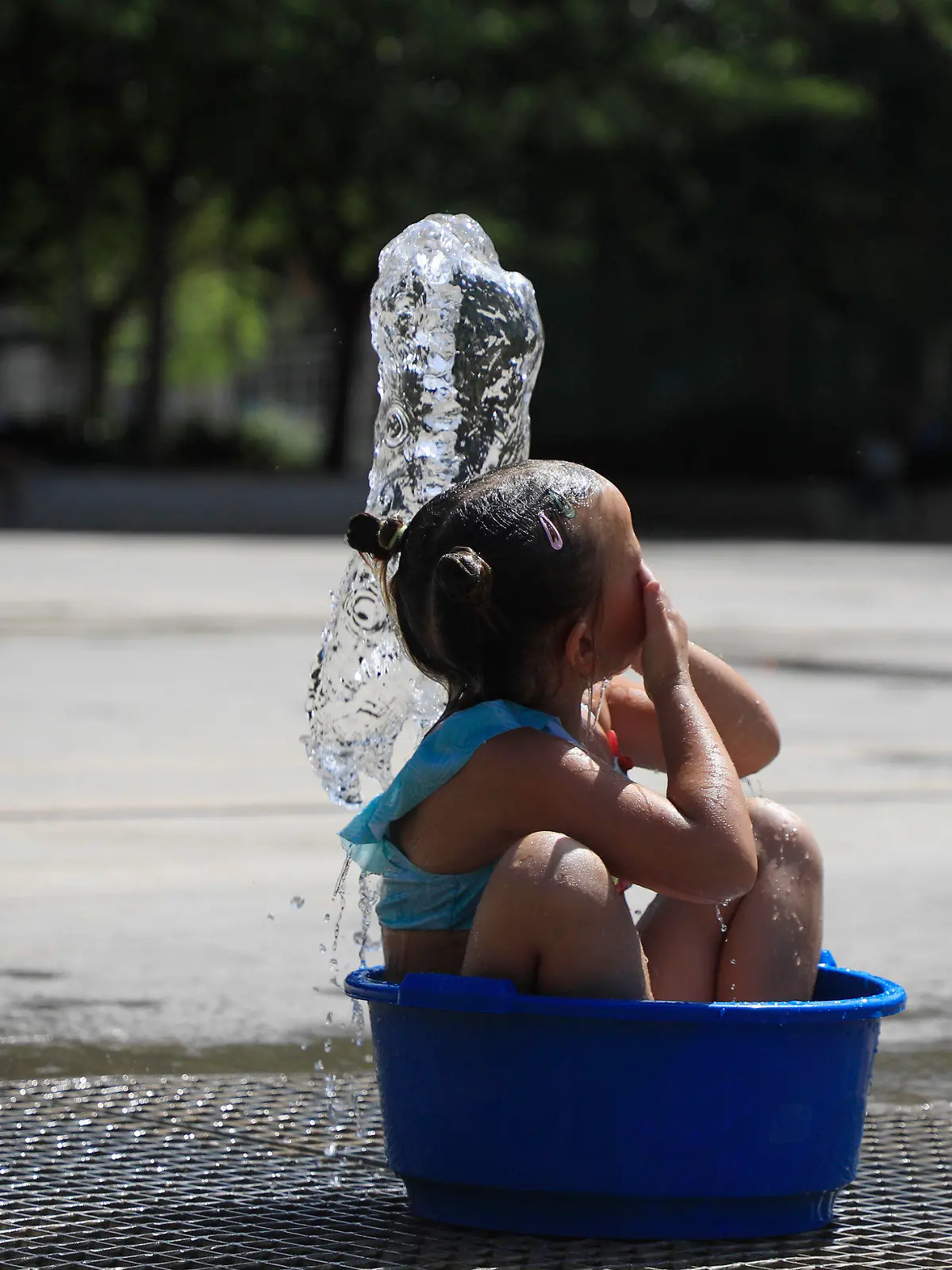 31.07.2024, Spanien, Palma: Ein Mädchen erfrischt sich bei Hitze in einem öffentlichen Brunnen. Foto: Clara Margais/dpa - ACHTUNG: Nur zur redaktionellen Verwendung im Zusammenhang mit der aktuellen Berichterstattung und nur mit vollständiger Nennung des vorstehenden Credits +++ dpa-Bildfunk +++
