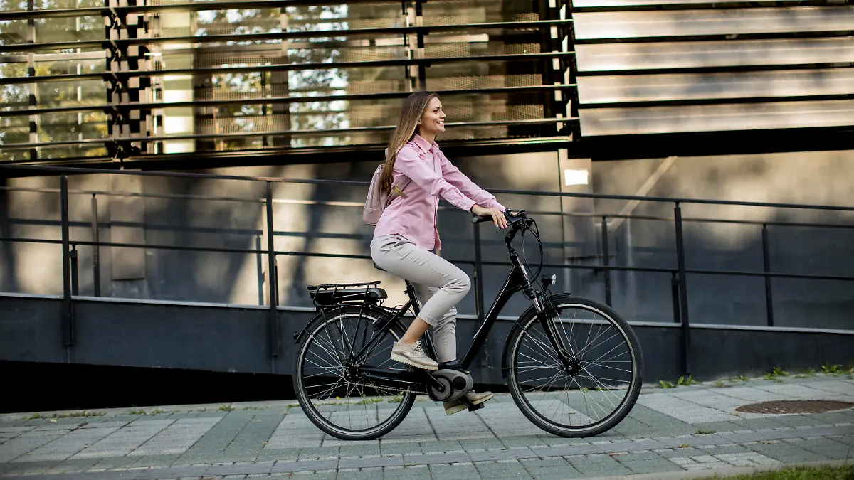 Young woman riding e bike in urban enviroment at sunny day