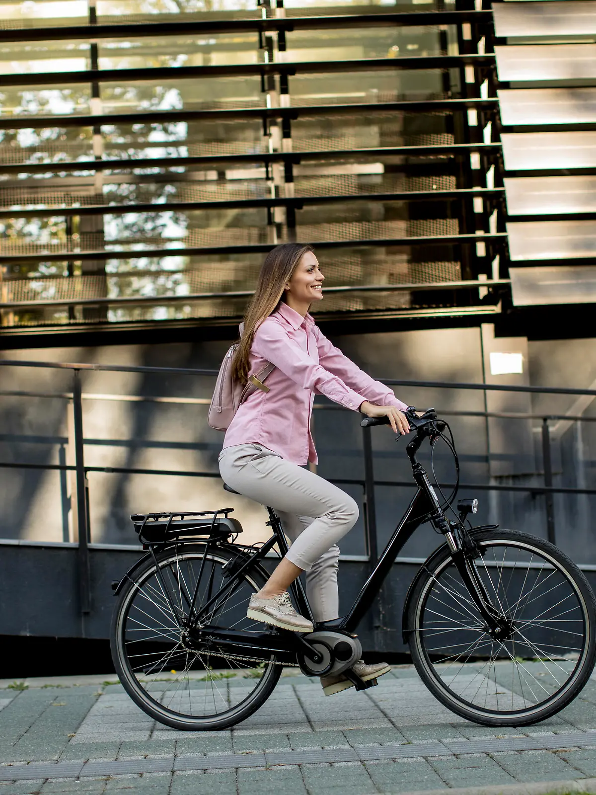 Young woman riding e bike in urban enviroment at sunny day
