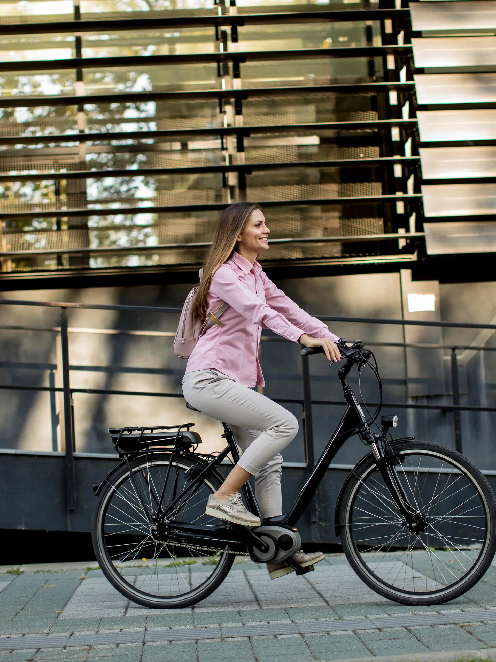 Young woman riding e bike in urban enviroment at sunny day
