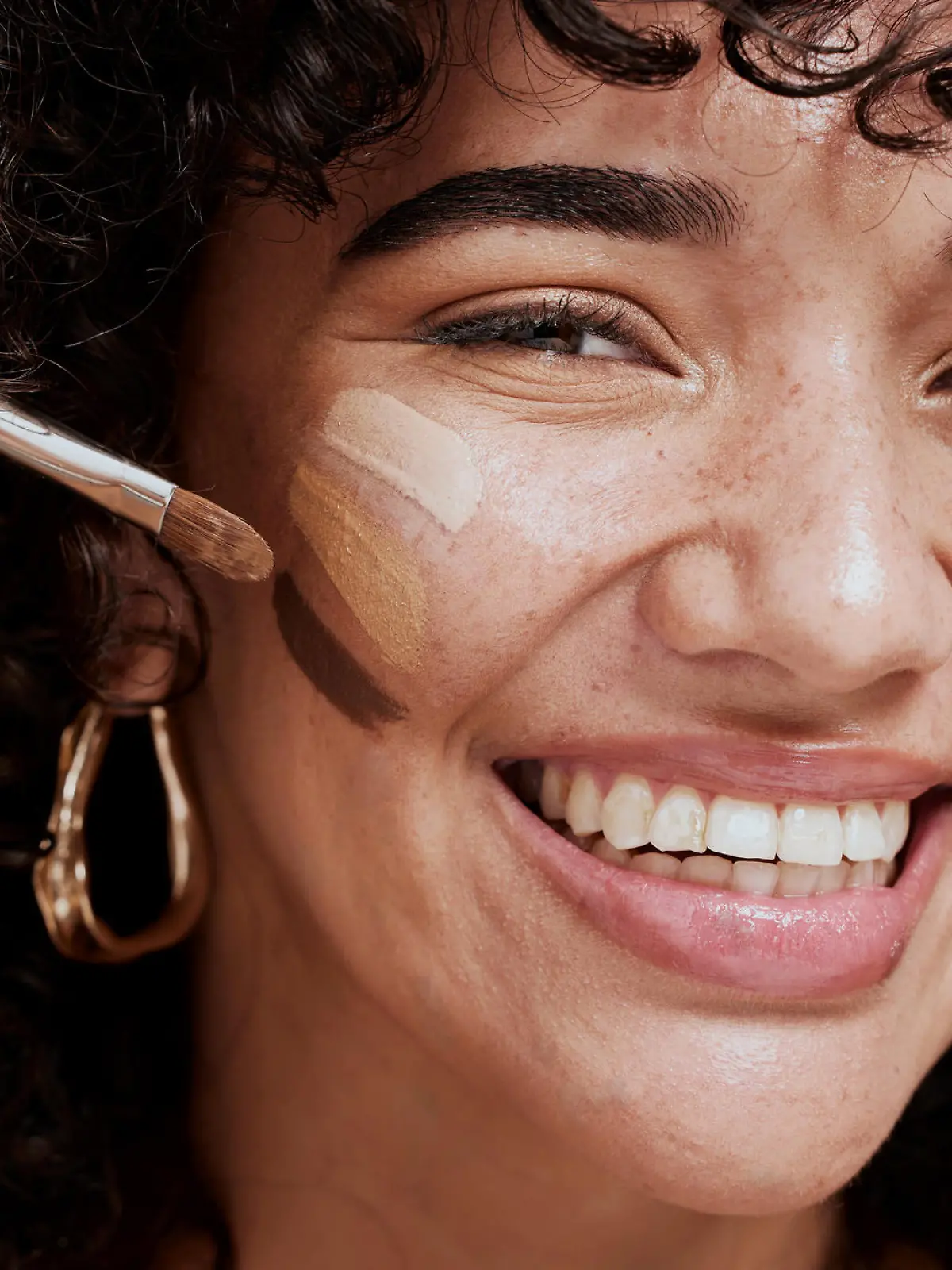 Face, makeup and brush with a woman black model applying foundation to her skin in studio for cosmetics. Portrait, wellness and luxury with an attractive young female using a cosmetic product