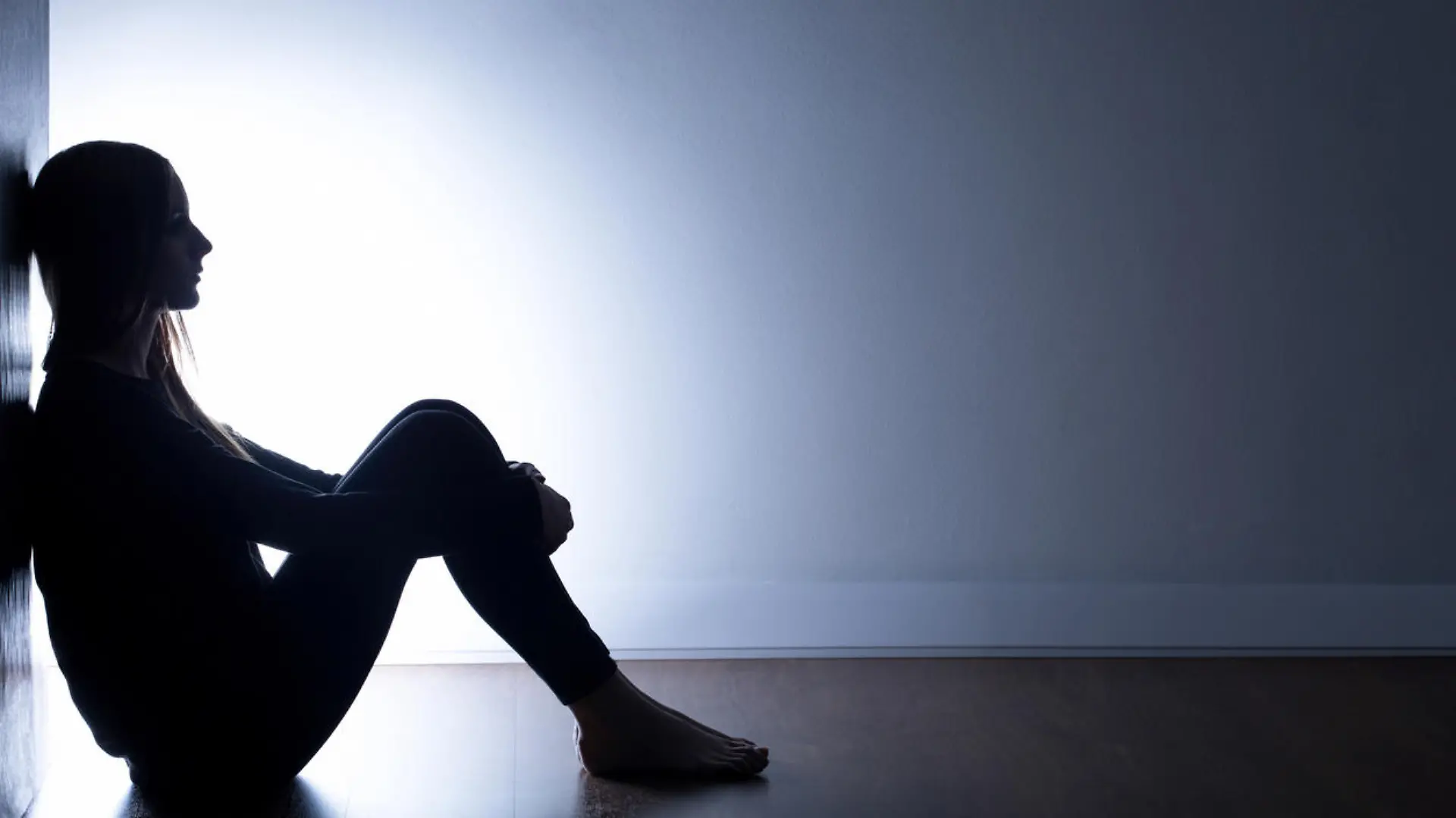 Teenager with depression sitting alone in dark room