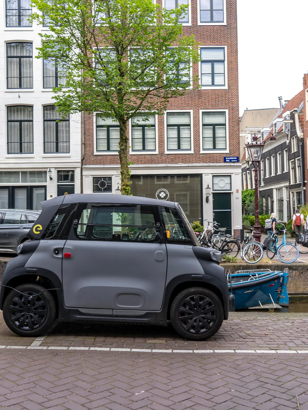 Miniauto in der Altstadt, Blauwburgwal Gracht, Innenstadt von Amsterdam, geparkt, Rocks Electric von Opel, E-Auto, beliebt in der Stadt, weil er wenig Parkraum braucht, darf am 15 Jahren Alter, mit Rollerführerschein, gefahren werden, Niederlande