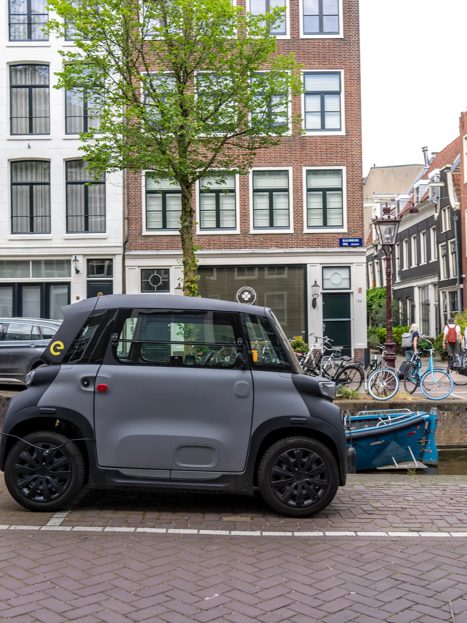 Miniauto in der Altstadt, Blauwburgwal Gracht, Innenstadt von Amsterdam, geparkt, Rocks Electric von Opel, E-Auto, beliebt in der Stadt, weil er wenig Parkraum braucht, darf am 15 Jahren Alter, mit Rollerführerschein, gefahren werden, Niederlande