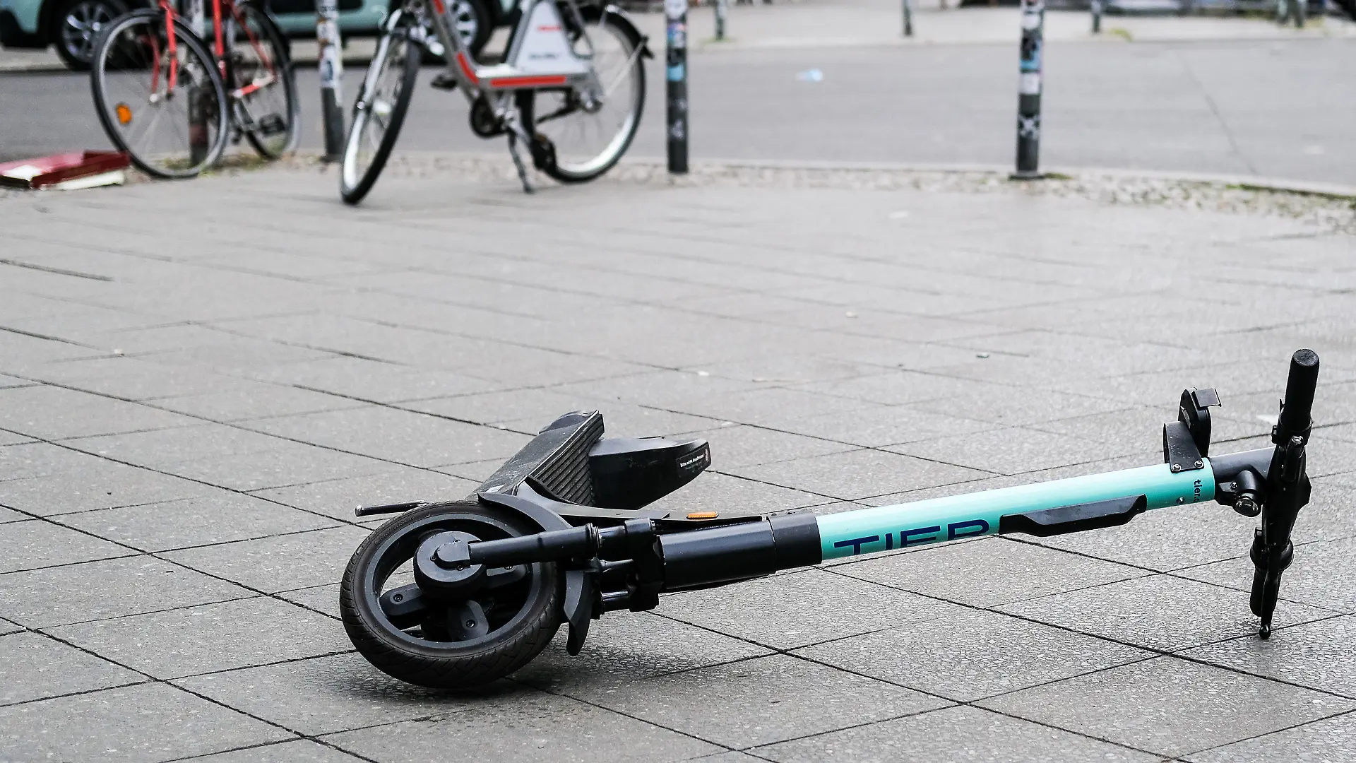 ARCHIV - 24.07.2020, Berlin: Ein E-Scooter liegt umgekippt mitten auf dem Gehweg in der Revaler Straße in Friedrichshain. Nach einem tödlichen Sturz eines Radfahrers über einen E-Roller in Gelsenkirchen ermittelt die Polizei weiter zum Hintergrund des Unfalls. (zu dpa: «Tödlicher Sturz von Radfahrer über E-Roller - Ermittlungen laufen») Foto: Jens Kalaene/dpa-Zentralbild/dpa +++ dpa-Bildfunk +++