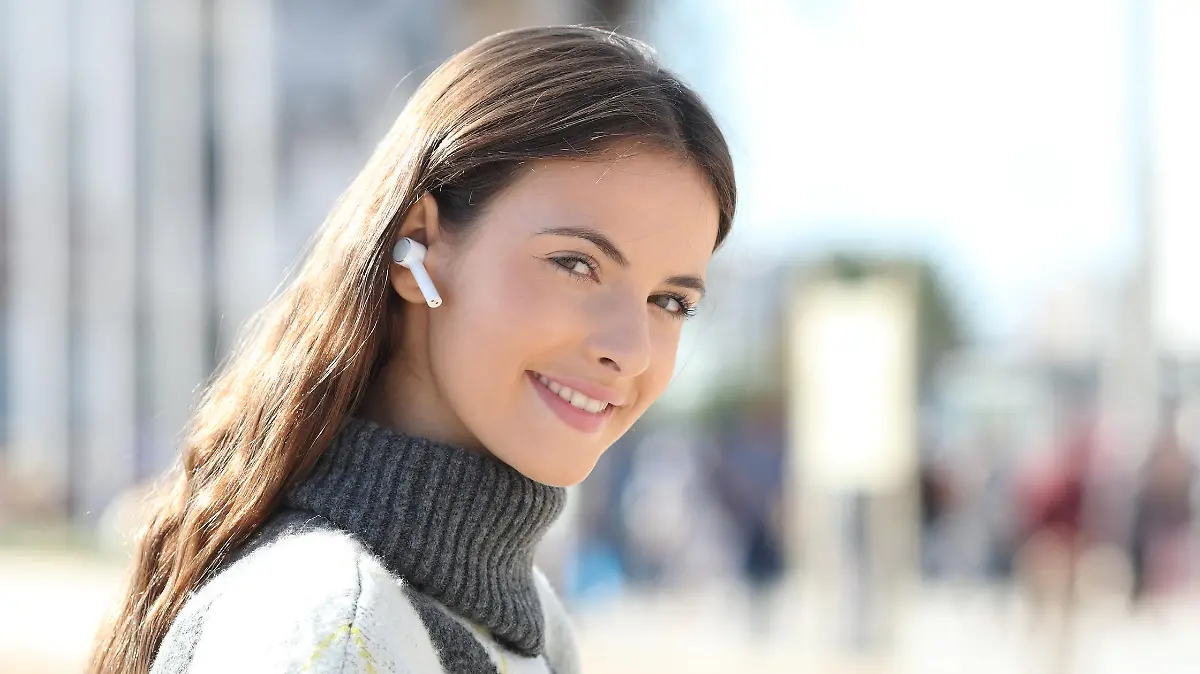 Happy girl holds phone listening to music looking at camera