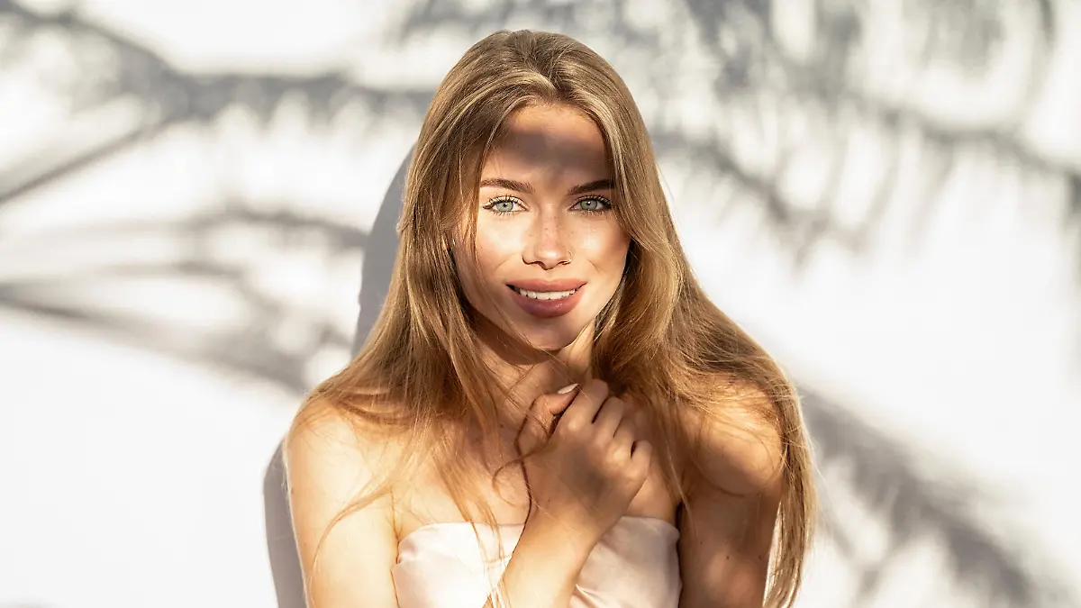 Lovely beautiful young blonde woman with natural freckles smiling to the camera. Natural shadows. A lot of copy space.
