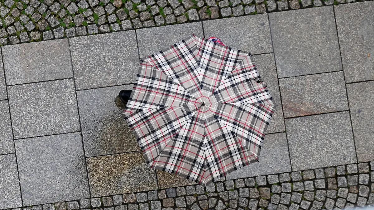 26.07.2024, Thüringen, Erfurt: Ein Mann mit Regenschirm läuft die Johannesstraße in der Erfurter Altstadt entlang. Der Start ins Wochenende wird ungemütlich nass und grau. Der Deutsche Wetterdienst (DWD) warnt für Thüringen in den nächsten Tagen vor kräftigen Gewittern, Starkregen bis zu 50 Litern pro Quadratmeter sowie Hagel. Foto: Martin Schutt/dpa +++ dpa-Bildfunk +++