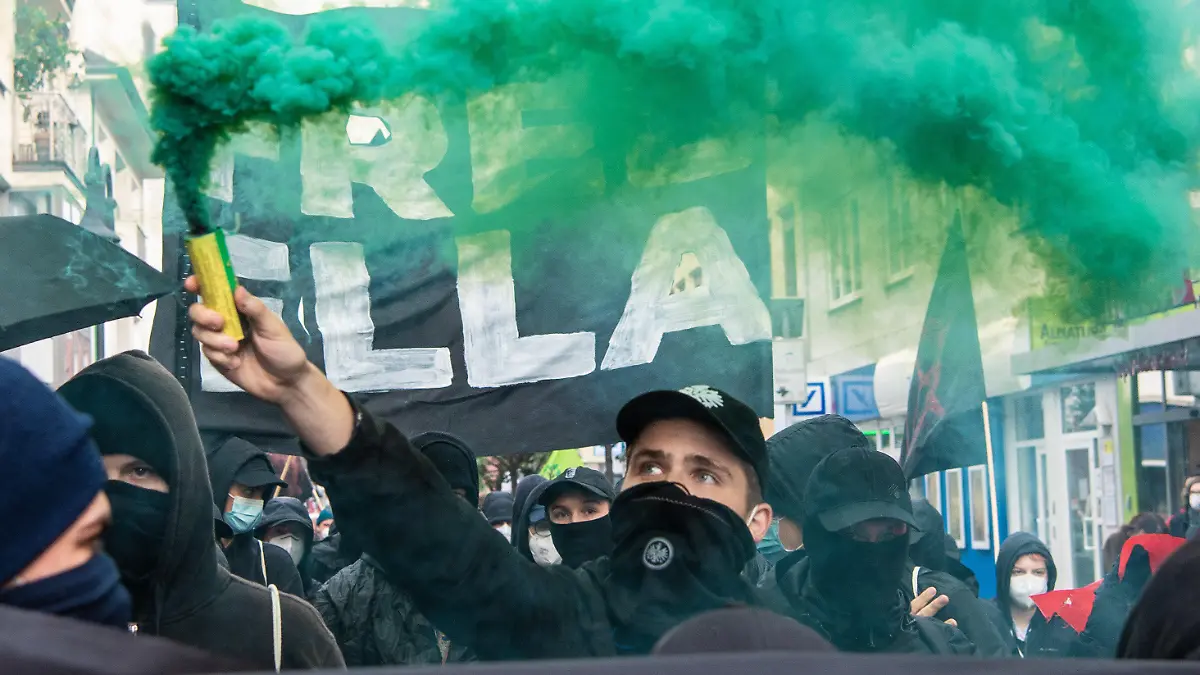 24.06.2021, Hessen, Frankfurt/Main: Mitglieder verschiedener Bündnisse aus der linken und Umweltschützer-Szene demonstrieren bei einem Umzug in Frankfurt-Bockenheim gegen die Haftstrafe für eine Aktivistin aus dem Dannenröder Forst. Dabei zünden sie Pyrotechnik und tragen ein Plakat mit der Aufschrift "Free Ella". Ein Gericht hatte die junge Frau, die sich weigert ihre Identität preiszugeben zu einer Freiheitsstrafe von mehr als zwei Jahren verurteilt. Die Aktivisten nennen die Frau "Ella". Foto: Boris Roessler/dpa +++ dpa-Bildfunk +++