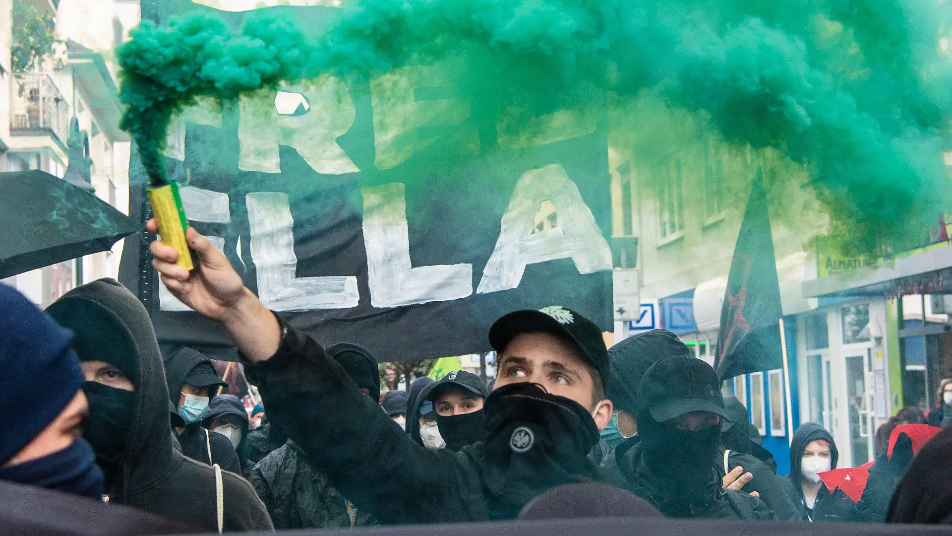 24.06.2021, Hessen, Frankfurt/Main: Mitglieder verschiedener Bündnisse aus der linken und Umweltschützer-Szene demonstrieren bei einem Umzug in Frankfurt-Bockenheim gegen die Haftstrafe für eine Aktivistin aus dem Dannenröder Forst. Dabei zünden sie Pyrotechnik und tragen ein Plakat mit der Aufschrift "Free Ella". Ein Gericht hatte die junge Frau, die sich weigert ihre Identität preiszugeben zu einer Freiheitsstrafe von mehr als zwei Jahren verurteilt. Die Aktivisten nennen die Frau "Ella". Foto: Boris Roessler/dpa +++ dpa-Bildfunk +++