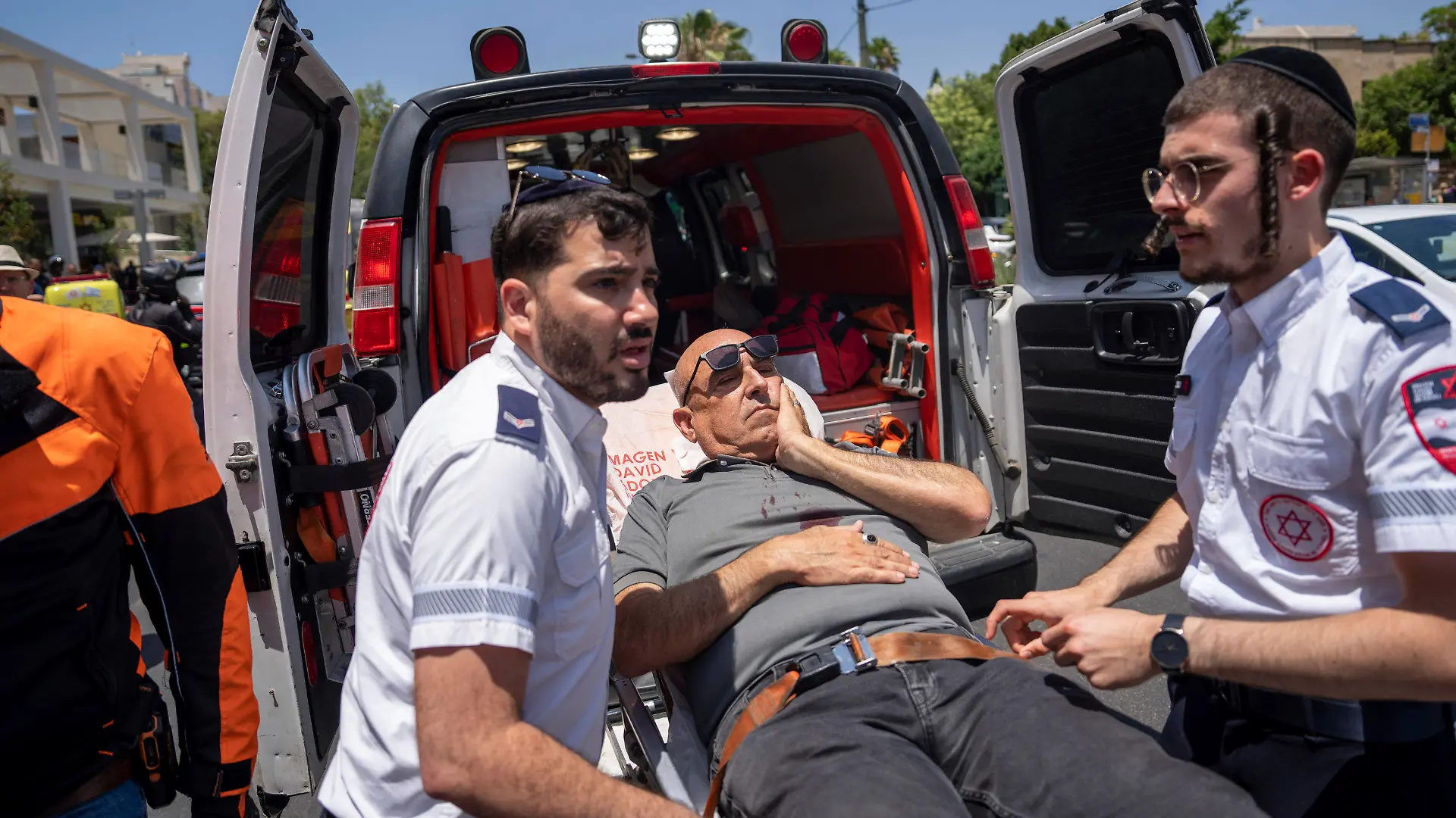 04.07.2023, Israel, Tel Aviv: Israelische Sanitäter evakuieren einen verletzten Mann an der Stelle, nachdem ein Auto in eine Grupe von Fußgängern gefahren ist. ei einem mutmaßlichen Anschlag in Tel Aviv sind mehrere Menschen verletzt worden. Ein Auto sei in eine Gruppe von Fußgängern gefahren, teilte der israelische Rettungsdienst Magen David Adom mit. Mindestens fünf Verletzte werden demnach derzeit vor Ort behandelt. Foto: Oded Balilty/AP/dpa +++ dpa-Bildfunk +++