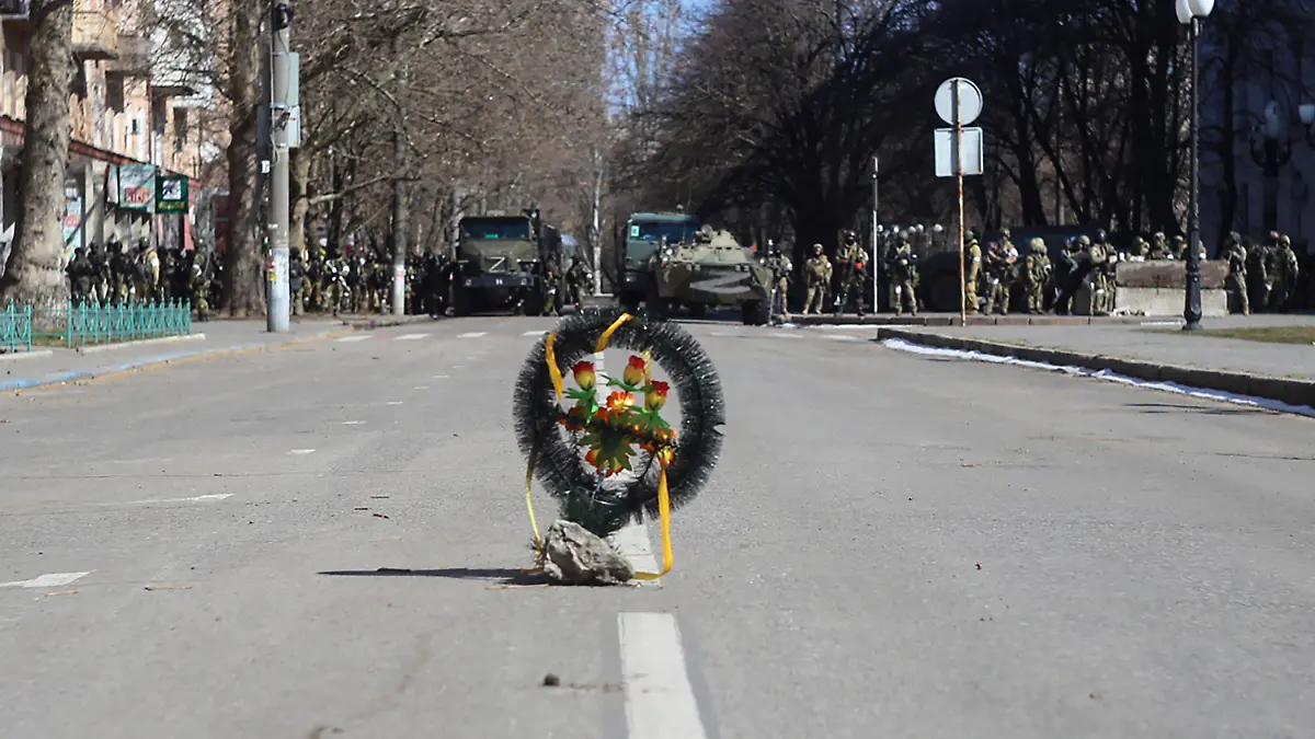 ARCHIV - 13.03.2022, Ukraine, Cherson: Ein Kranz mit Blumen steht am 13. März 2022 in Cherson bei einer Kundgebung gegen die russische Besatzung auf einer Straße während Soldaten der russischen Armee neben ihren Lastwagen stehen. Zuletzt hatte sich Spekulationen verstärkt, dass im südrussischen Gebiet Cherson ein Referendum zur Abspaltung organisiert werden soll. Gegen diesen Plan protestierten die Bewohner Chersons bereits im März. Foto: Olexandr Chornyi/AP/dpa +++ dpa-Bildfunk +++