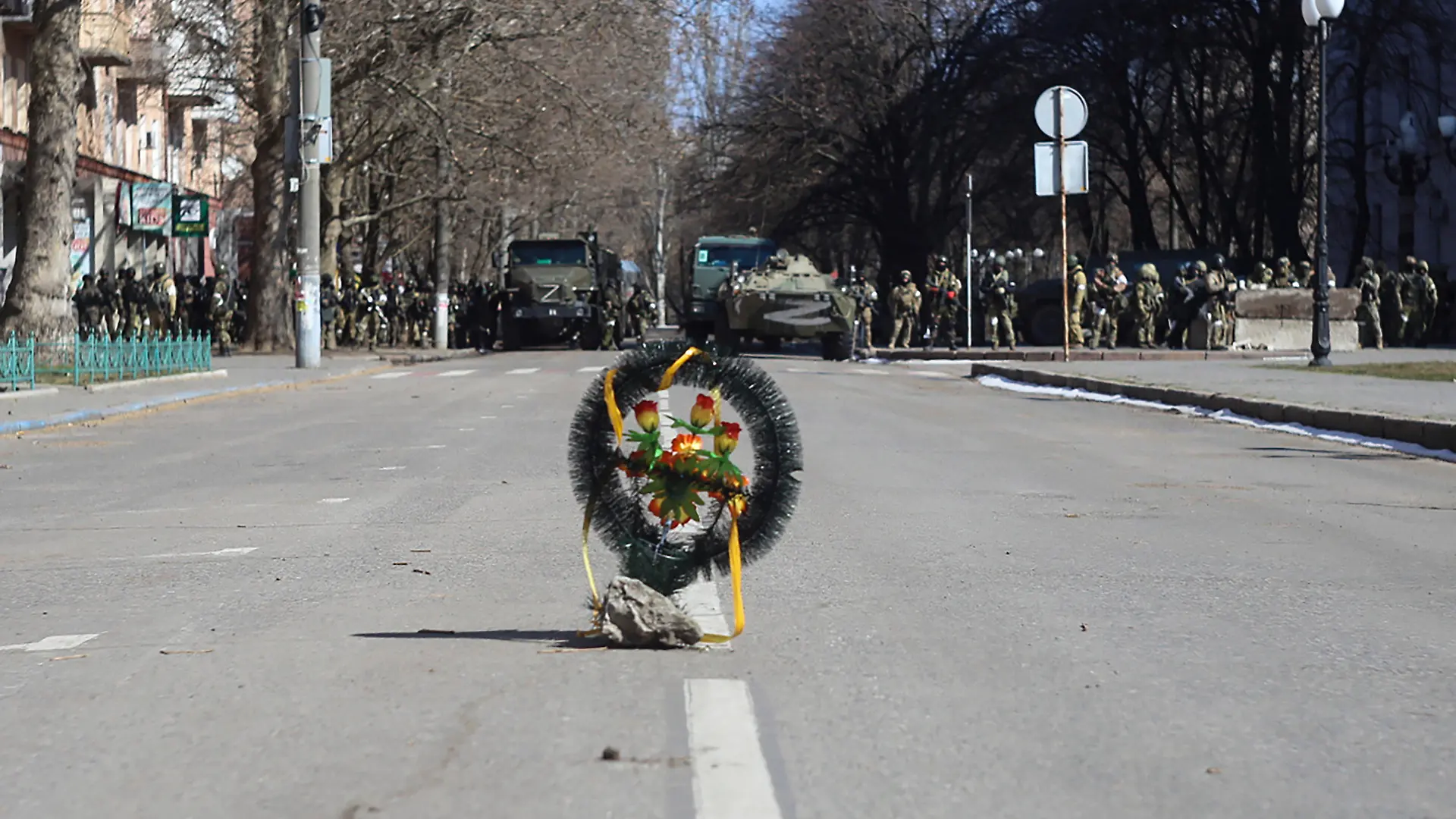 ARCHIV - 13.03.2022, Ukraine, Cherson: Ein Kranz mit Blumen steht am 13. März 2022 in Cherson bei einer Kundgebung gegen die russische Besatzung auf einer Straße während Soldaten der russischen Armee neben ihren Lastwagen stehen. Zuletzt hatte sich Spekulationen verstärkt, dass im südrussischen Gebiet Cherson ein Referendum zur Abspaltung organisiert werden soll. Gegen diesen Plan protestierten die Bewohner Chersons bereits im März. Foto: Olexandr Chornyi/AP/dpa +++ dpa-Bildfunk +++