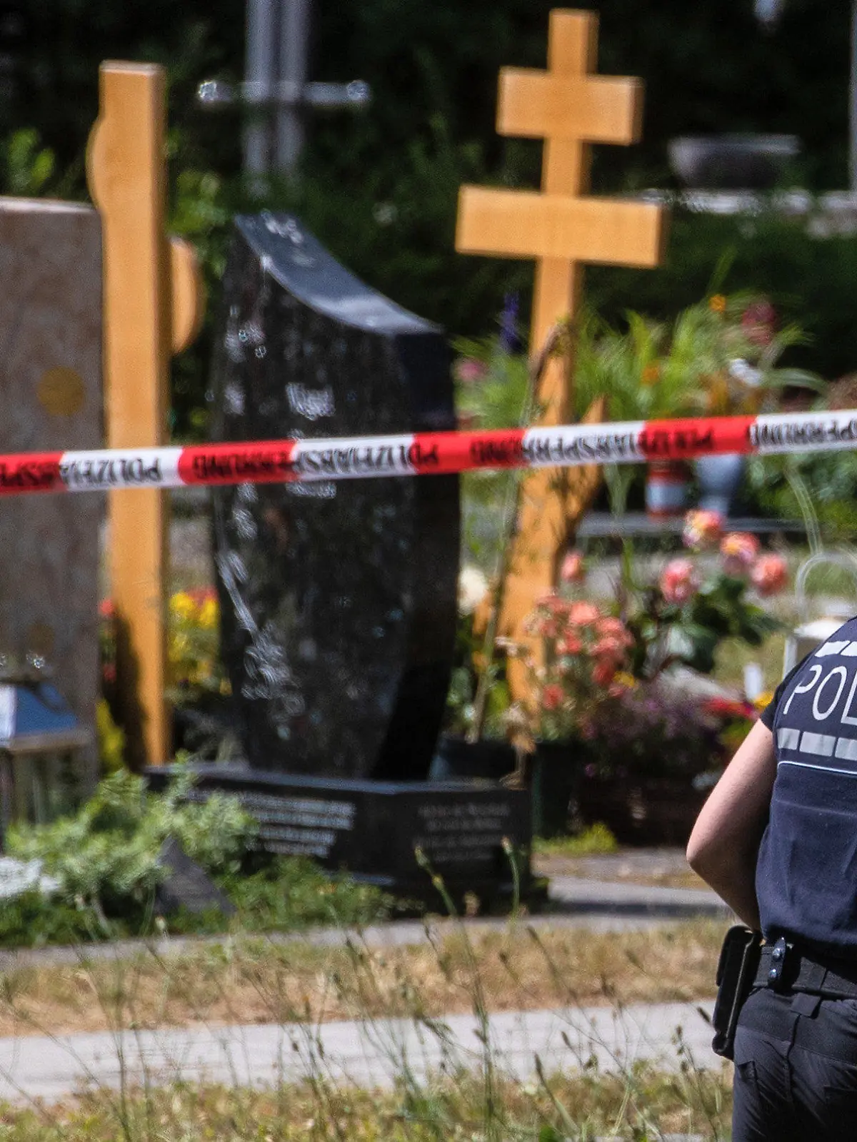 09.06.2023, Baden-Württemberg, Altbach: Eine Polizistin geht über den abgesperrten Teil an einem Tatort auf einem Friedhof. Durch den Wurf eines explodierenden Gegenstands auf eine Trauergemeinde gab es mehrere Verletzte. (Wiederholung mit verändertem Bildausschnitt) Foto: Christoph Schmidt/dpa +++ dpa-Bildfunk +++