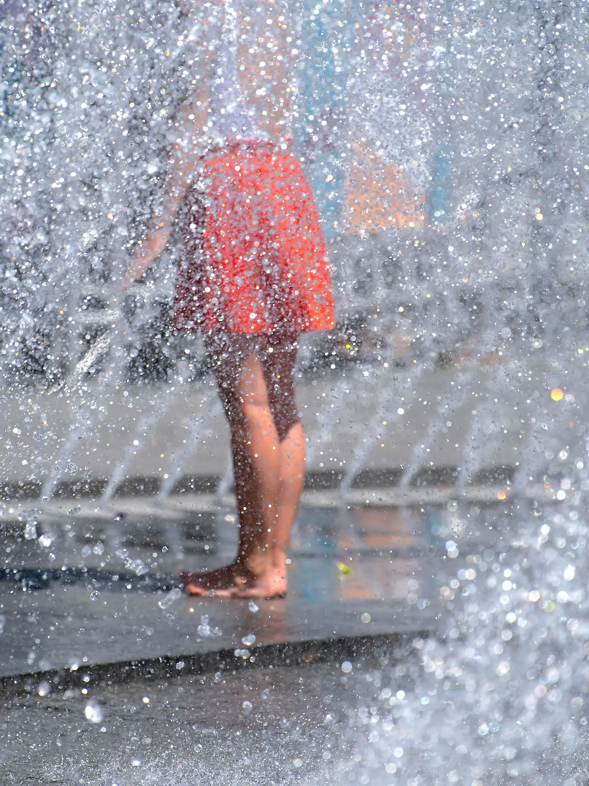 Eine Frau kühlt sich an einem Springbrunnen am Karlsplatz (Stachus) ab.