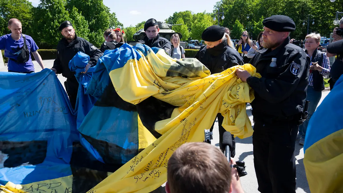 08.05.2022, Berlin: Polizisten wickeln eine große Ukrainische Fahne bei einer Gedenkveranstaltung vor dem Sowjetischen Ehrenmal im Tiergarten zusammen. Foto: Christophe Gateau/dpa +++ dpa-Bildfunk +++