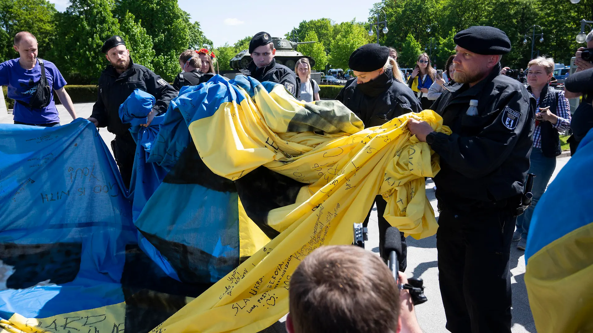 08.05.2022, Berlin: Polizisten wickeln eine große Ukrainische Fahne bei einer Gedenkveranstaltung vor dem Sowjetischen Ehrenmal im Tiergarten zusammen. Foto: Christophe Gateau/dpa +++ dpa-Bildfunk +++