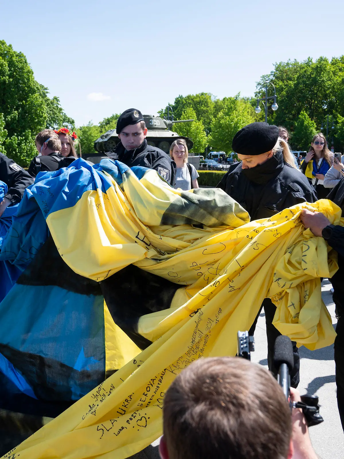 08.05.2022, Berlin: Polizisten wickeln eine große Ukrainische Fahne bei einer Gedenkveranstaltung vor dem Sowjetischen Ehrenmal im Tiergarten zusammen. Foto: Christophe Gateau/dpa +++ dpa-Bildfunk +++