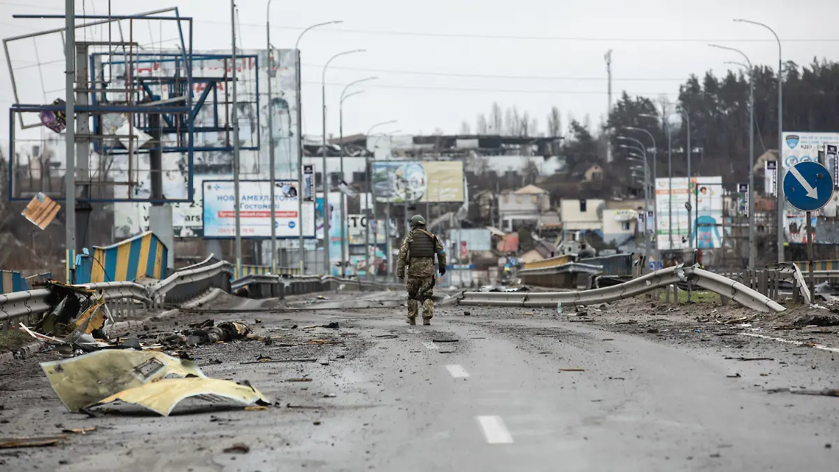 02.04.2022, Ukraine, Bucha: Ein ukrainischer Soldat geht entlang von Leichen auf einer zerstörten Straße. Fast 300 Zivilisten wurden entlang der Straße Butscha, einer Pendlerstadt außerhalb der Hauptstadt, getötet. Die meisten Opfer versuchten, den Fluss Buchanka zu überqueren, um in das ukrainisch kontrollierte Gebiet zu gelangen, und wurden dabei getötet. Russland ist am 24. Februar 2022 in die Ukraine einmarschiert und hat damit den größten Militärangriff in Europa seit dem Zweiten Weltkrieg ausgelöst. Foto: Mykhaylo Palinchak/SOPA Images via ZUMA Press Wire/dpa +++ dpa-Bildfunk +++