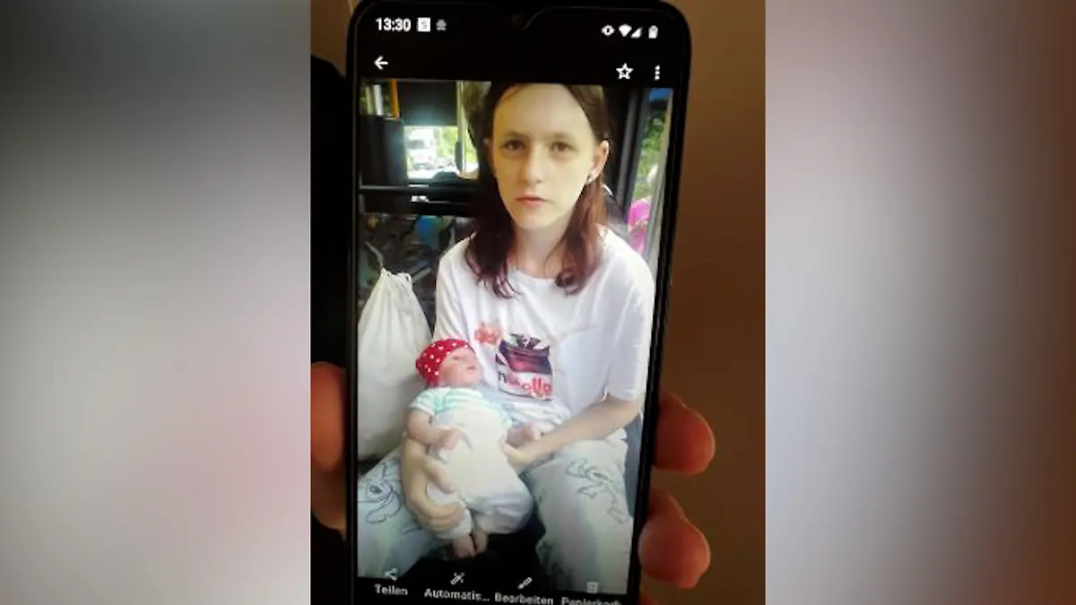 Auf dem Bild ist eine Jugendliche zu sehen, die allerdings Kleidung im Stil eines Kindes trägt. Sie hat eine Puppe in der Hand.