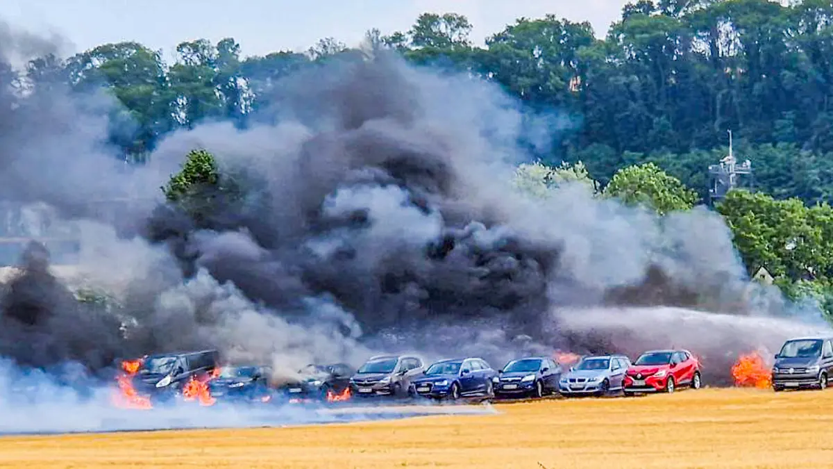 02.07.2023, Baden-Württemberg, Bad Wimpfen: Einsatzkräfte der Feuerwehr löschen auf einem Behelfsparkplatz ein Feuer. Mindestens zwölf Autos seien bei dem Brand am Sonntag durch Flammen und Hitze beschädigt worden, einige davon auch schwer. Foto: ER24/EinsatzReport24/dpa +++ dpa-Bildfunk +++