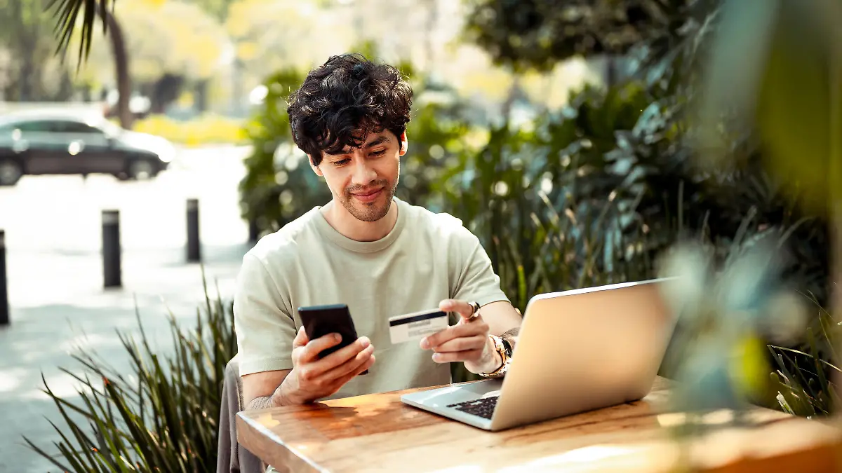 Young man sitting at the cafe and paying online with credit card