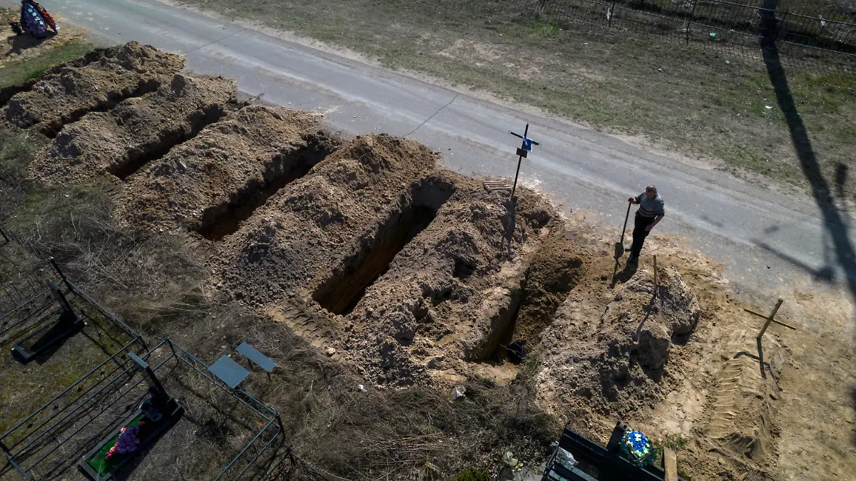 14.04.2022, Ukraine, Butscha: Ein Friedhofsarbeiter steht auf einem Friedhof neben frisch ausgehobenen Gräbern. Foto: Rodrigo Abd/AP/dpa +++ dpa-Bildfunk +++