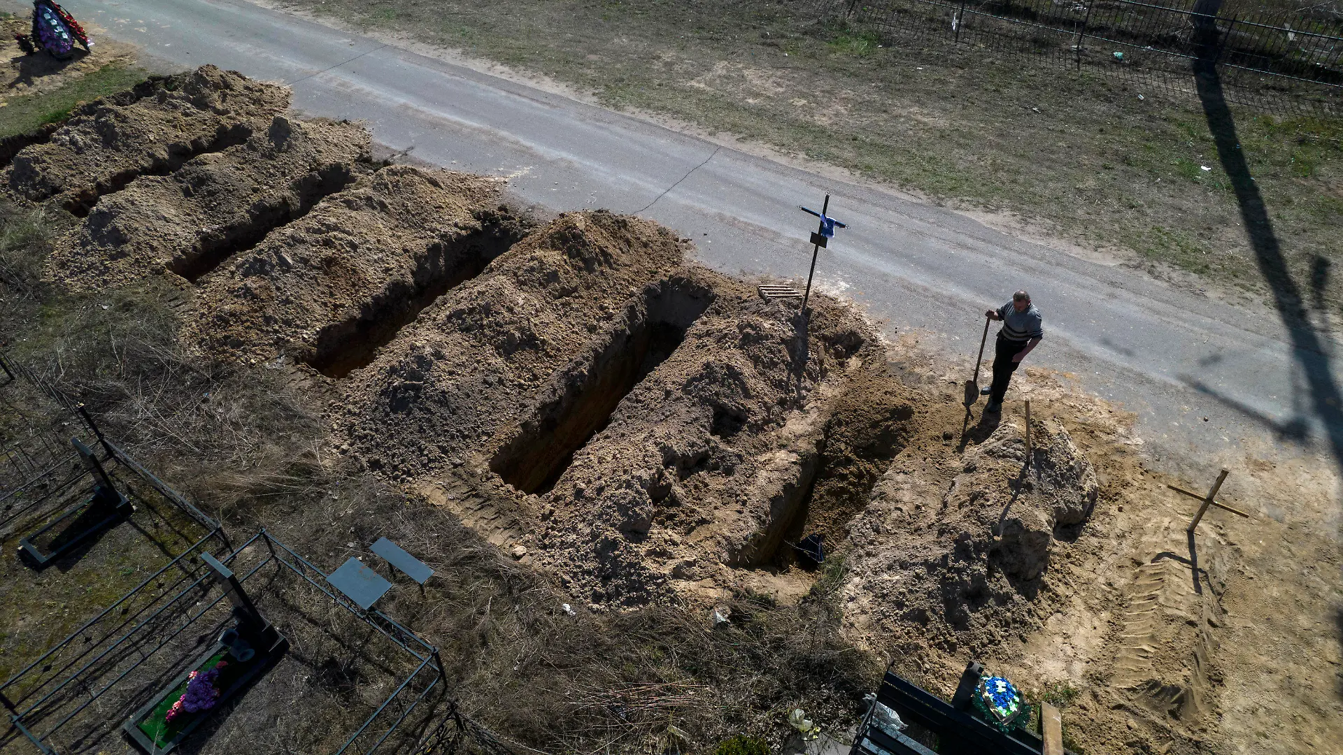 14.04.2022, Ukraine, Butscha: Ein Friedhofsarbeiter steht auf einem Friedhof neben frisch ausgehobenen Gräbern. Foto: Rodrigo Abd/AP/dpa +++ dpa-Bildfunk +++
