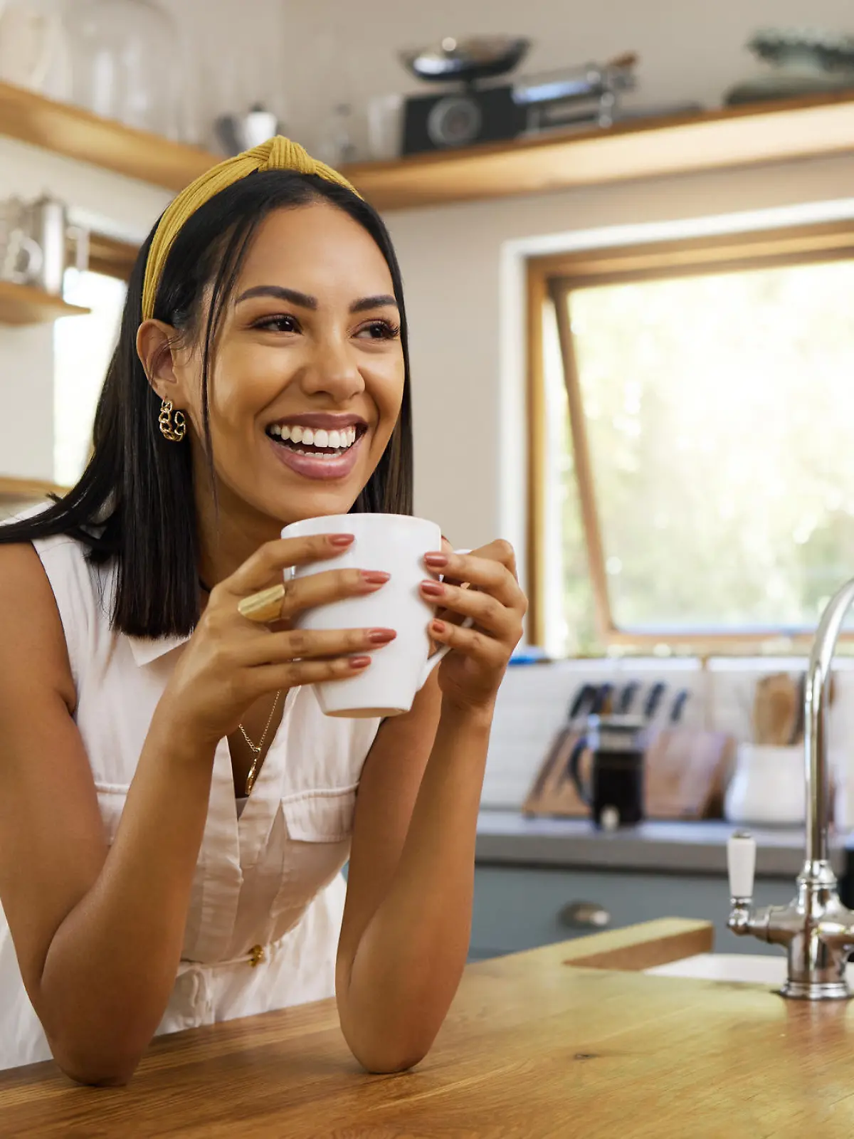 Happy woman, coffee or tea in home kitchen and relax with a smile in the morning at house. Calm young person, smiling at peace and caffeine drink to wake up to start day with positive productive vibe