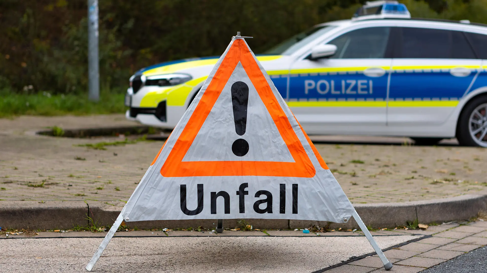 Deutschland 13. Oktober 2022: An einer Straße steht ein faltbares Warndreieck der Polizei mit der Aufschrift Unfall. Im Hintergrund steht ein Einsatzfahrzeug, Streifenwagen der Polizei mit Blaulicht und Schriftzug. Niedersachsen *** Germany 13 October 2022 On a road is a foldable warning triangle of the police with the inscription accident In the background is an emergency vehicle, police patrol car with blue lights and lettering Lower Saxony Copyright: xFotostandx/xGelhotx