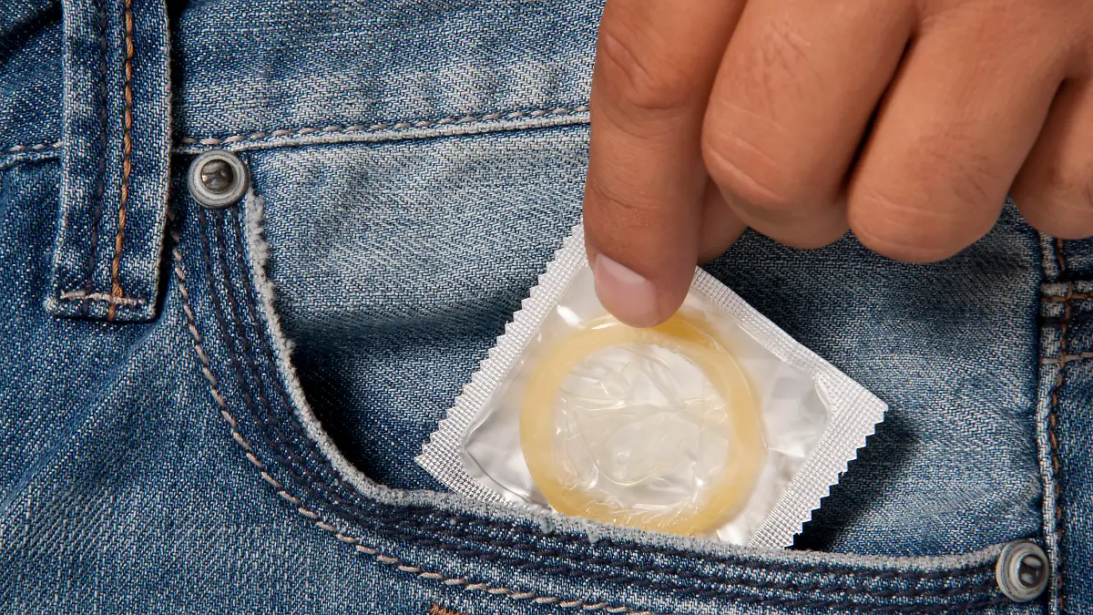 Junge Frau zieht Kondom aus Jeanstasche. 