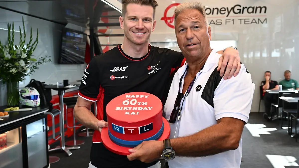 Haas-Pilot Nico Hülkenberg (l.) und RTL-Reporter Kai Ebel posieren mit roter Geburtstagstorte auf der ein RTL-Logo zu sehen ist.