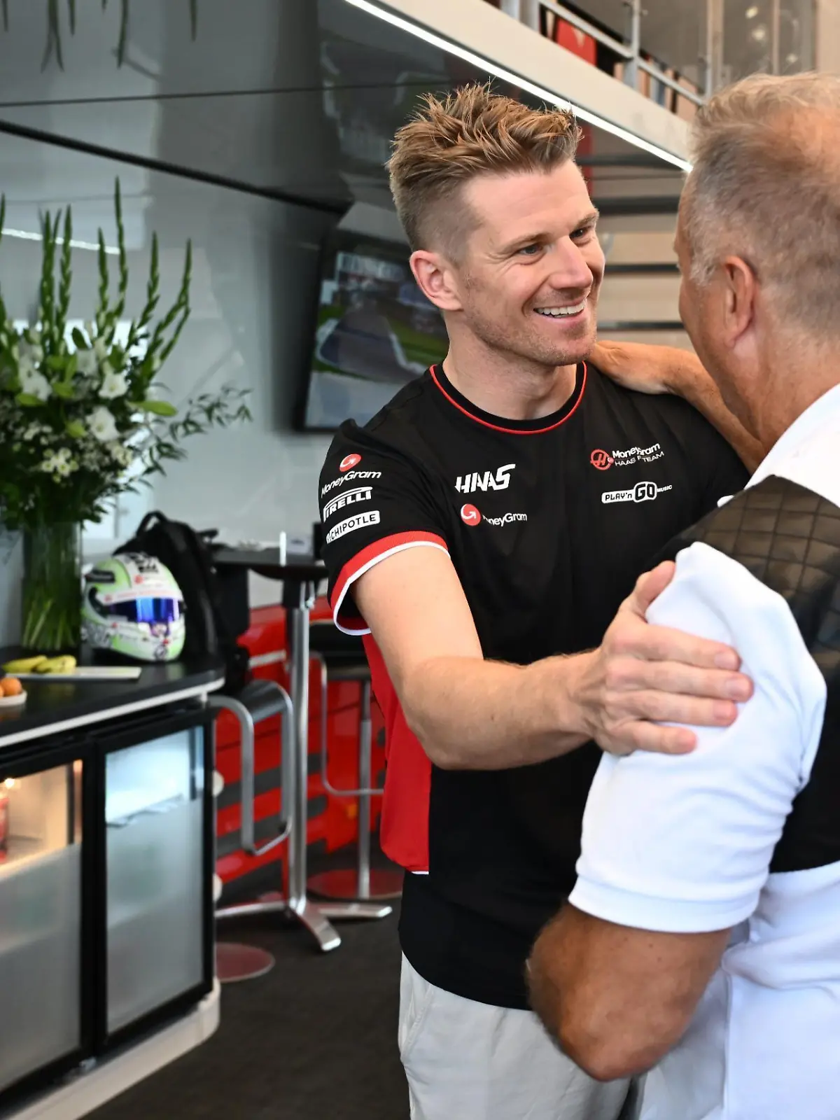 Haas-Pilot Nico Hülkenberg (l.) legt RTL-Reporter Kai Ebel die Hand auf die Schulter und gratuliert ihm zum 60. Geburtstag
