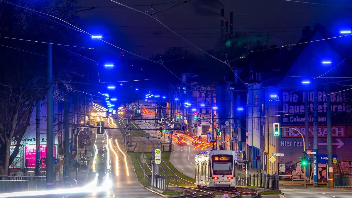 Eine Straßenbahn fährt entlang der Kurt-Schumacher-Straße in Gelsenkirchen bei Nacht.