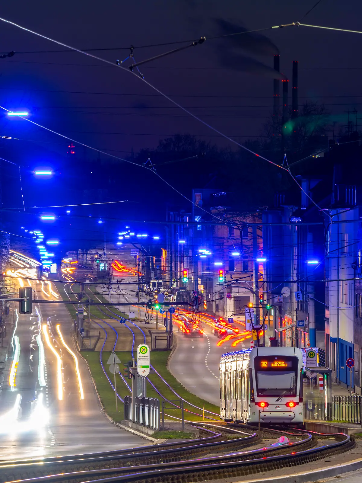 Eine Straßenbahn fährt entlang der Kurt-Schumacher-Straße in Gelsenkirchen bei Nacht. 