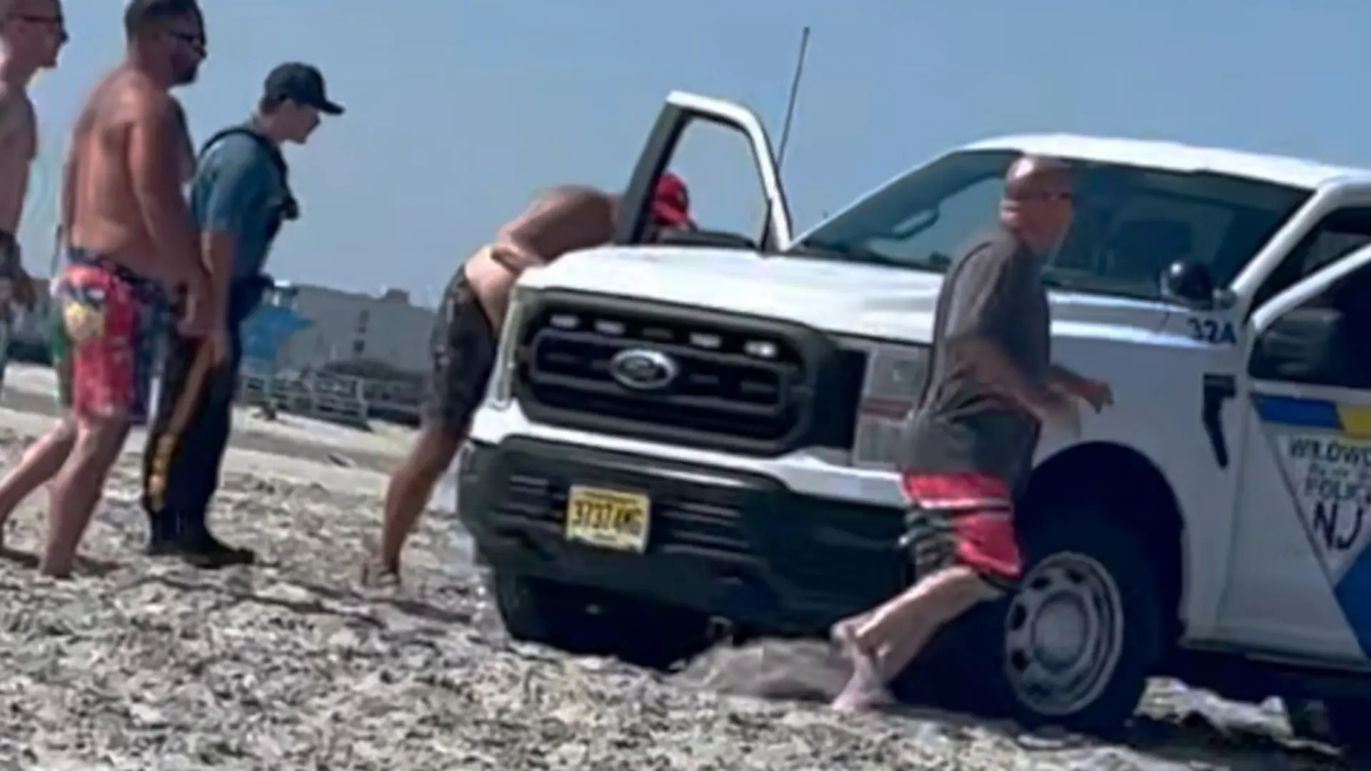 Ein Polizei-Truck am Strand, daneben Menschen.