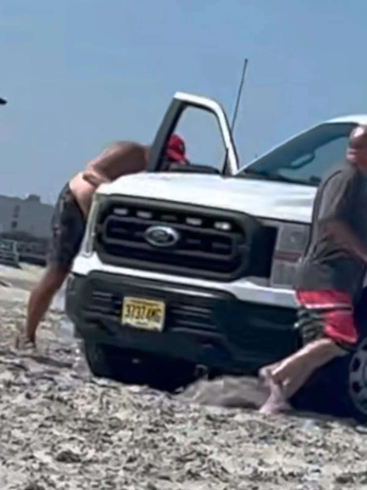 Ein Polizei-Truck am Strand, daneben Menschen. 