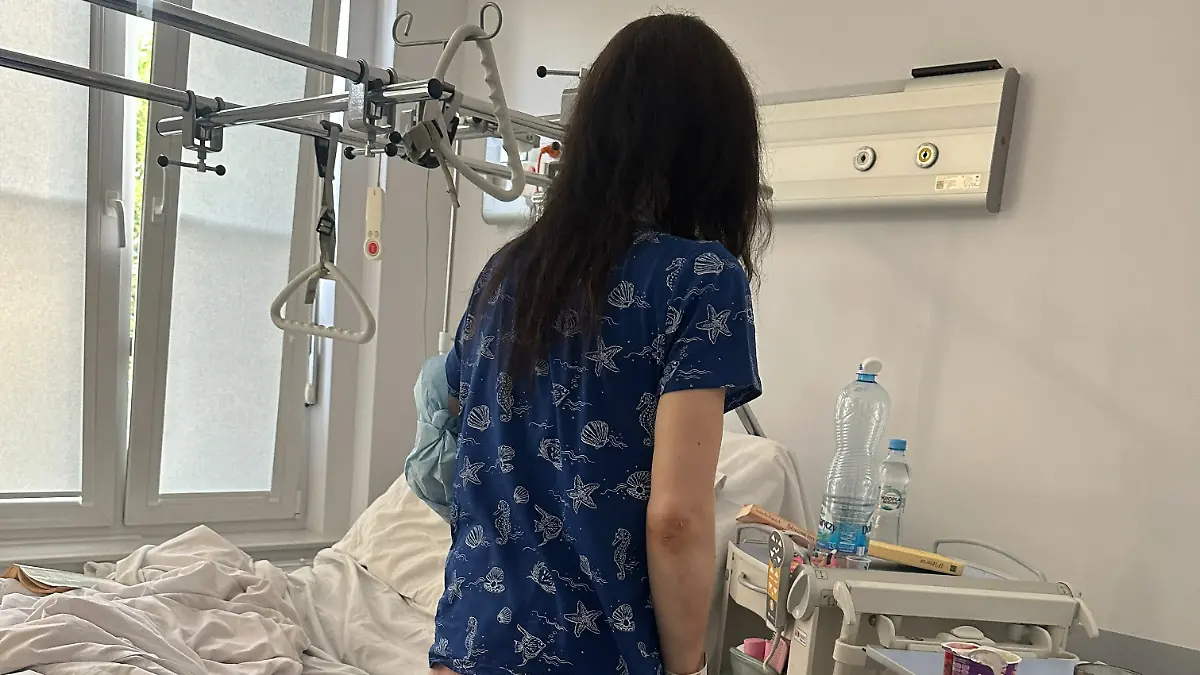 Eine Frau steht vor einem Krankenbett.