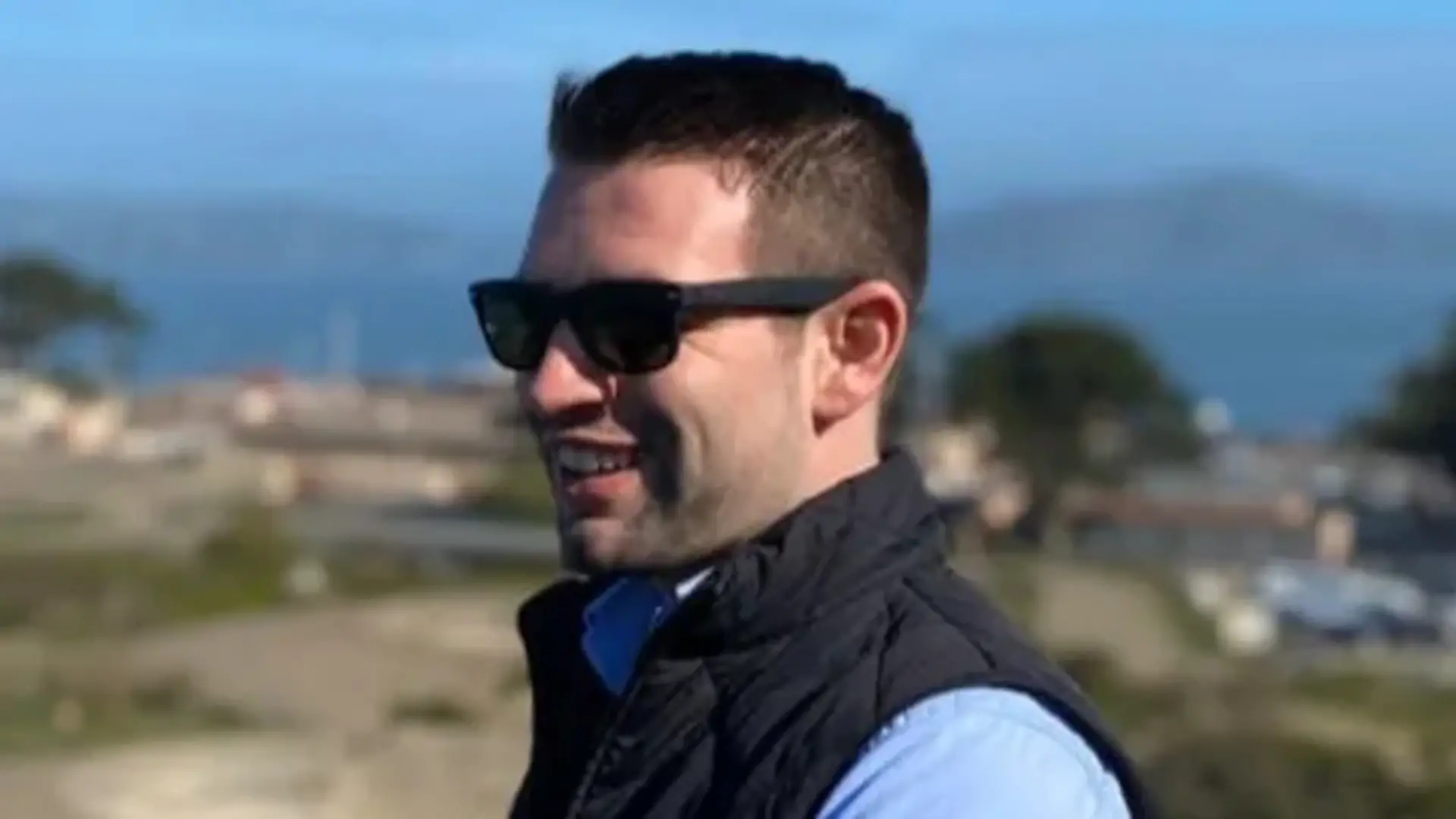 Gabe H. trägt eine Sonnenbrille und lächelt in die Kamera.