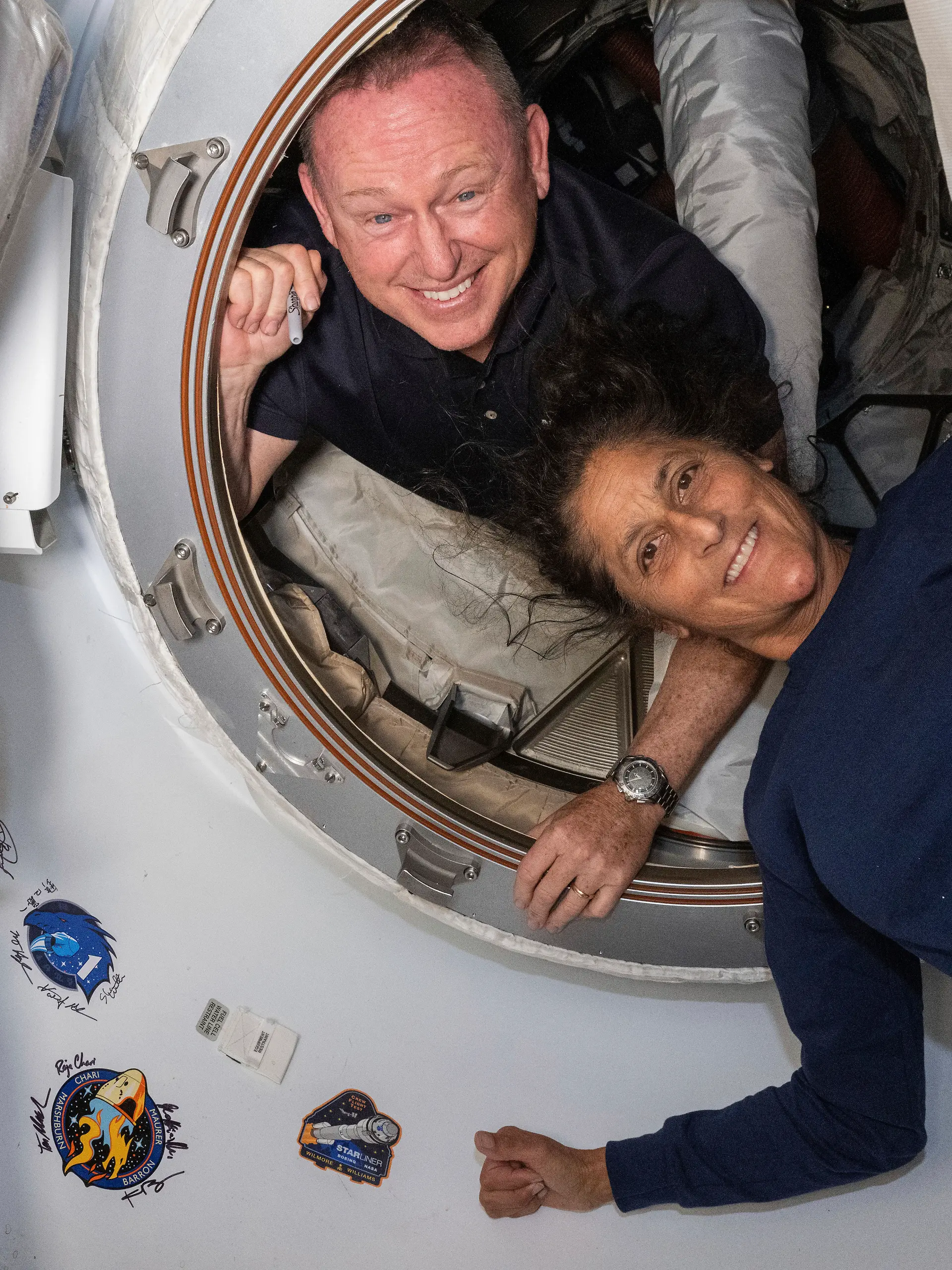 Die Astronauten Butch Wilmore und Suni Williams befinden sich an Bord der ISS und lächeln in die Kamera.