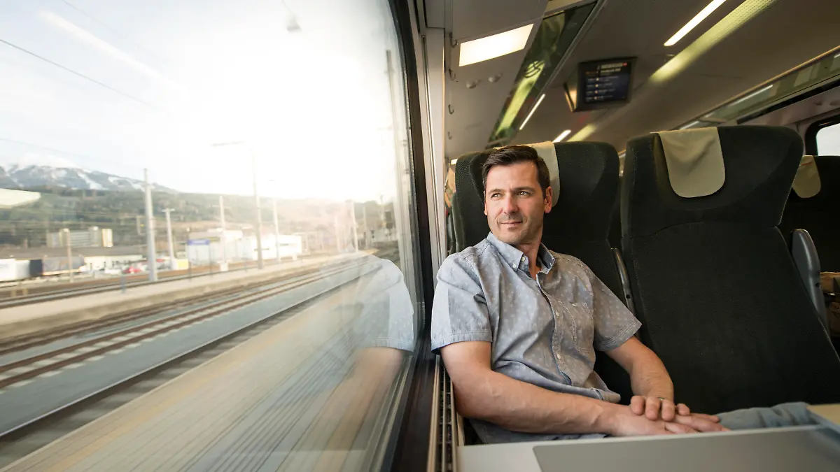 Serious businessman looking out of window while he is traveling by train.
