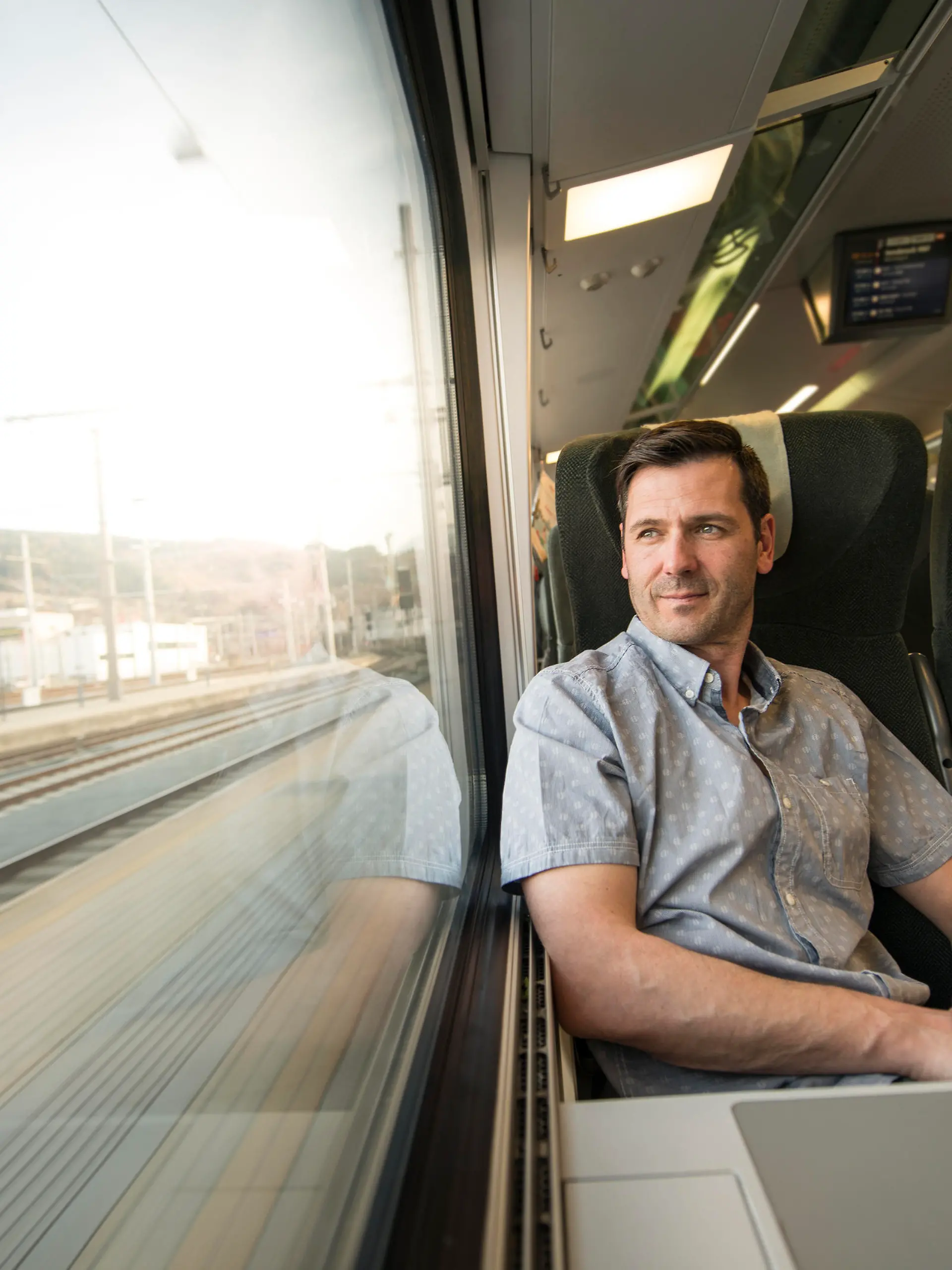 Serious businessman looking out of window while he is traveling by train.